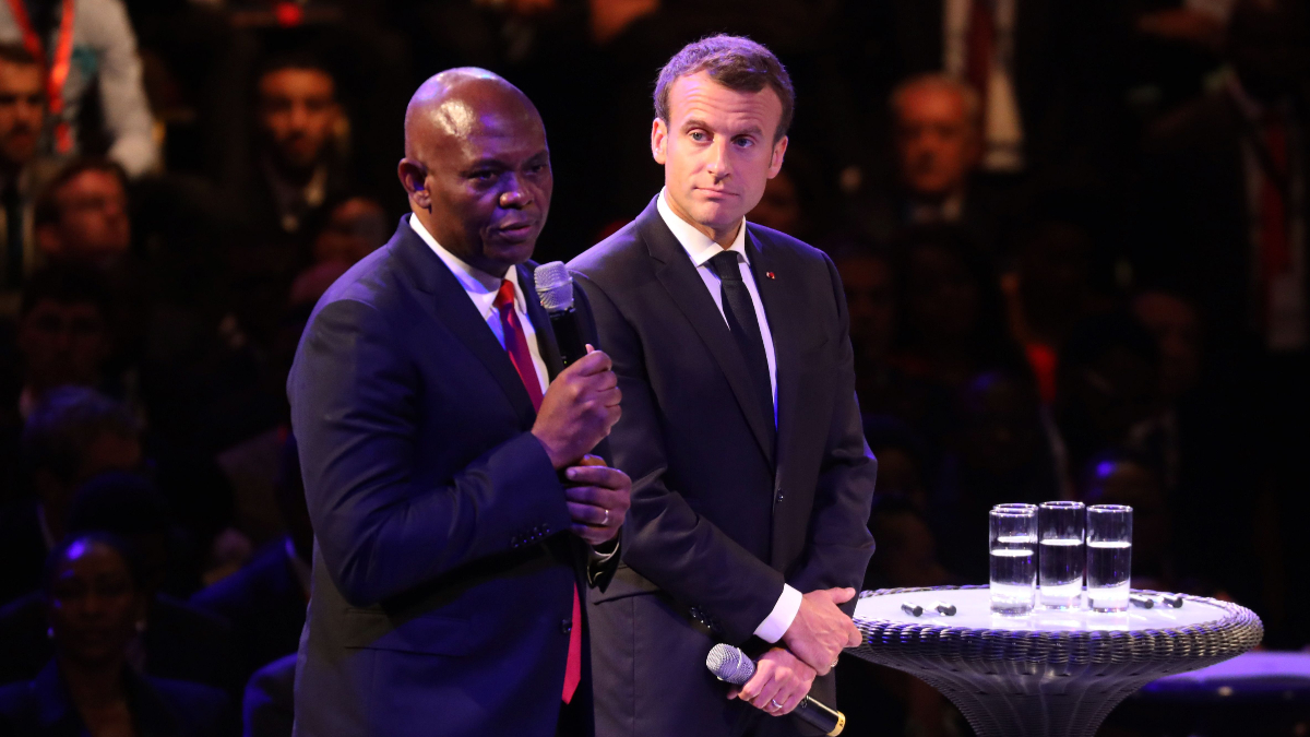 French President Emmanuel Macron (R) looks on as Nigerian businessman and economist Tony Elumelu delivers a speech to entrepreneurs at a convention centre in Lagos on July 4, 2018. [Photo by LUDOVIC MARIN/AFP via Getty Images]