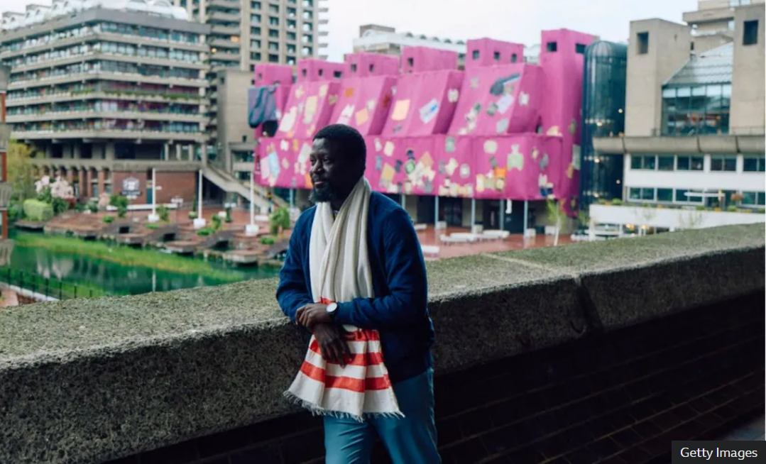 Ibrahim Mahama poses with latest art work at the Barbican center in London