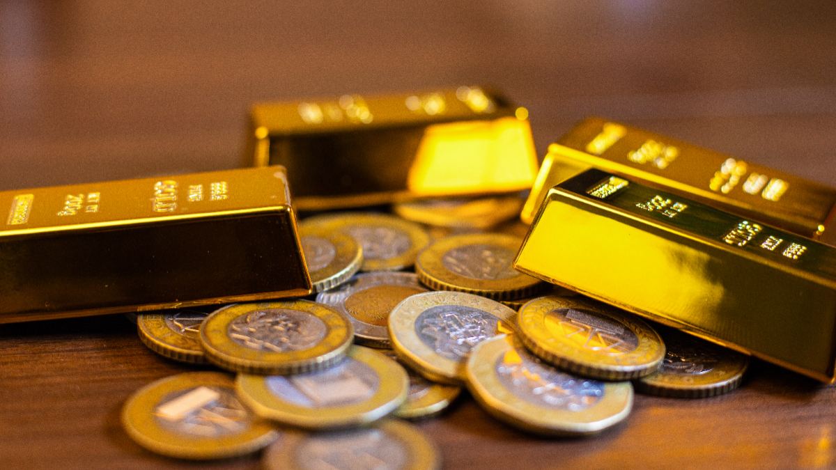 Image featuring several gold bars resting on top of a pile of Ghanaian cedi coins. [Stock Photos/Getty Images]