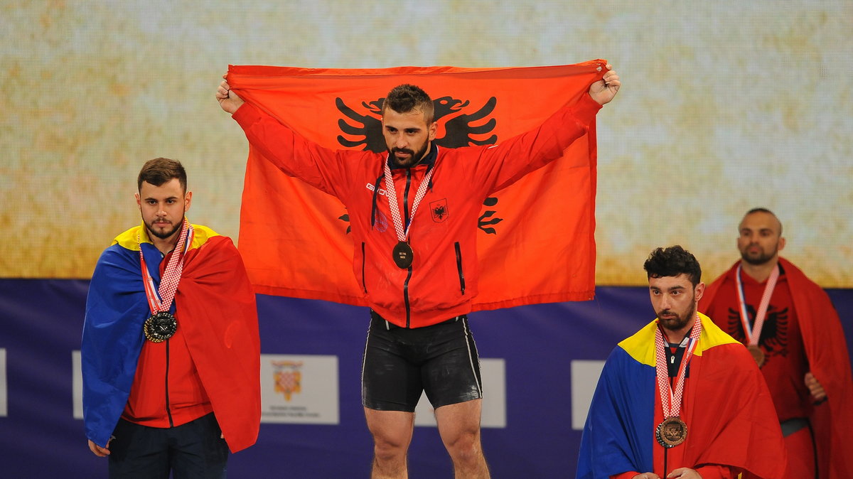 Daniel Godell z Albanii z flagą swojego kraju na podium