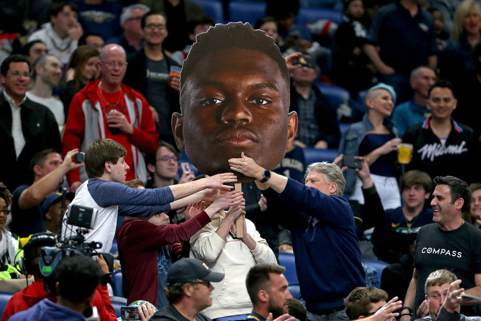 Fani New Orleans Pelicans trzymający plakat z twarzą Ziona Williamsona w Smoothie King Center