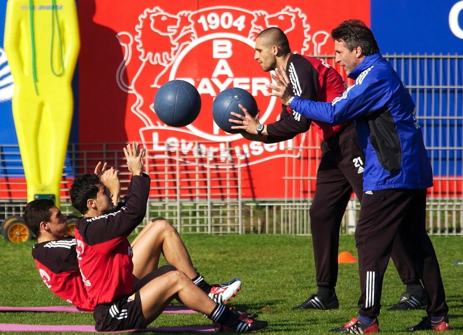 Radosław Kałużny oraz trener Thomas Horster (obaj stoją) rzucają piłkami z Lucio oraz Yildirayem Bastuerkiem podczas treningu Bayeru Leverkusen (15 kwietnia 2003 r.)