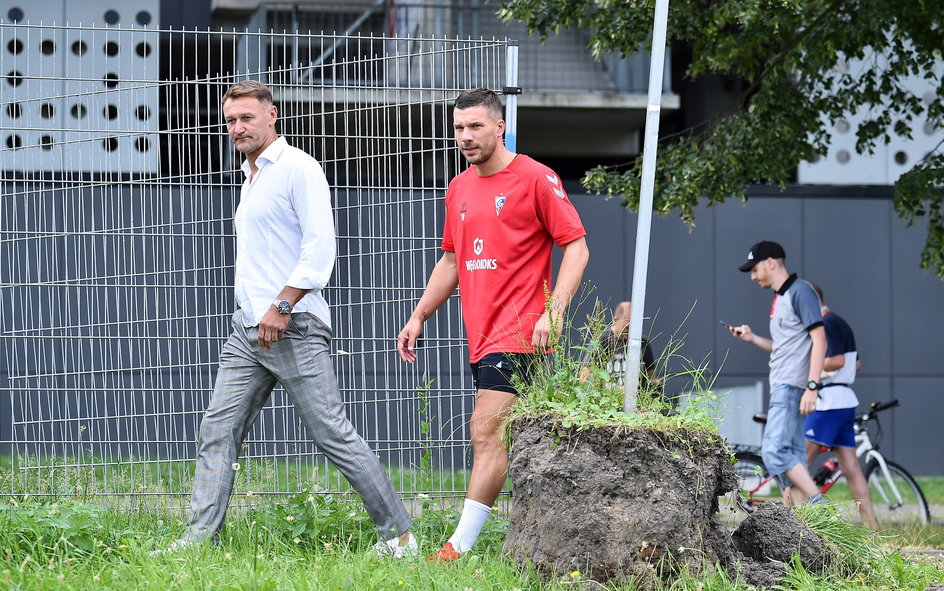 Artur Płatek idzie z Lukasem Podolskim na jego pierwszy trening w Górniku.