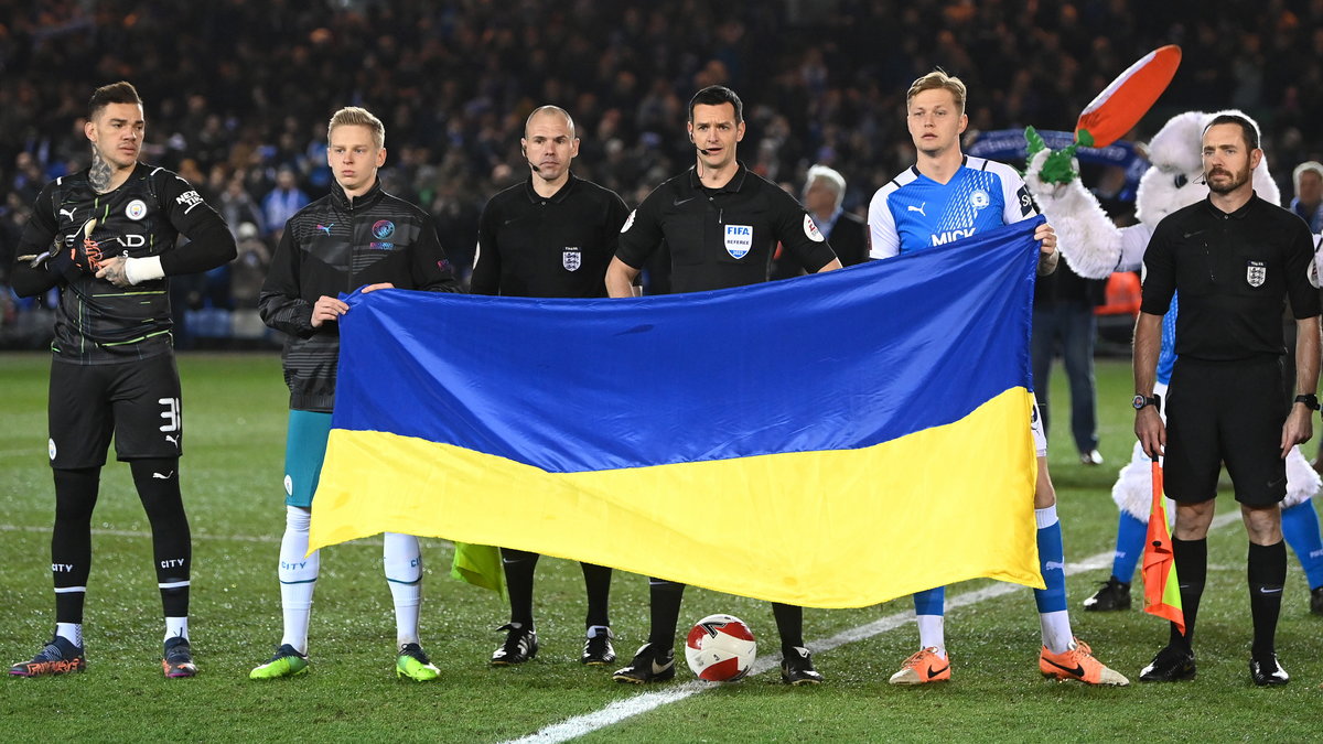 Piłkarze wyszli na murawę, trzymając flagę Ukrainy