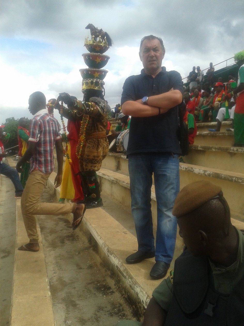 Bogusław Baniak na stadionie w Mali, gdzie gościł z reprezentacją Burkina Faso juniorów, za nim szaman tamtejszej reprezentacji