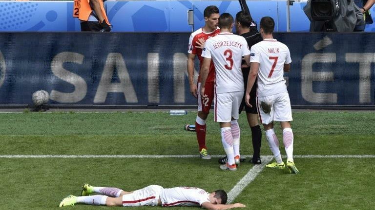 English referee Mark Clattenburg (Top) gives Switzerland's defender Fabian Schaer (top-L) a yellow card after a tackle on Poland's forward Robert Lewandowski (bottom) during the Euro 2016 round of sixteen football match Switzerland vs Poland