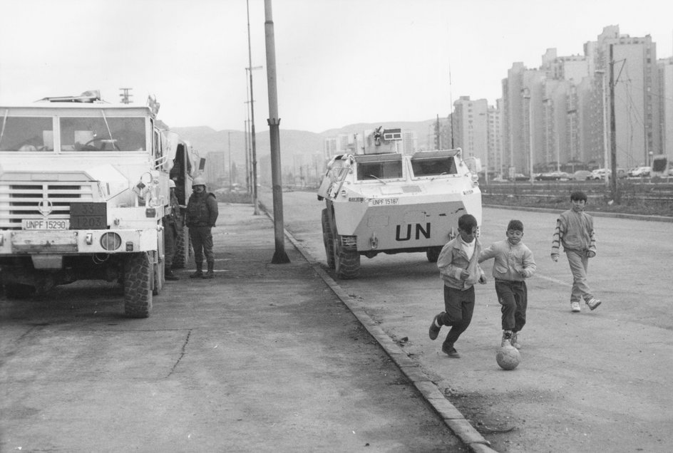 Dzieci grające w piłkę na tle pojazdu ONZ (Sarajewo, 1993 r.)