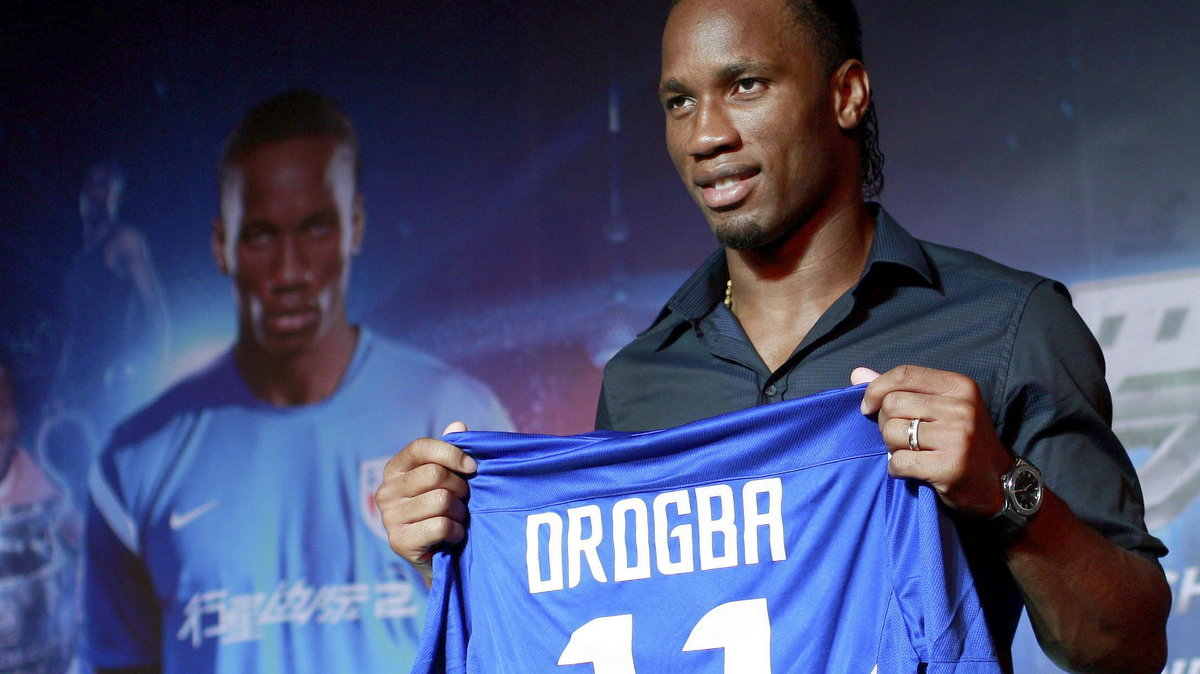 Soccer player Didier Drogba holds up a Shanghai Shenhua FC jersey during a news conference in Shanghai