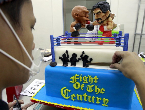 Cake decorator places details on a two-layer cake featuring fondant caricatures of boxers Pacquiao of the Philippines and Mayweather of the U.S. inside a boxing ring at a bakery in Manila