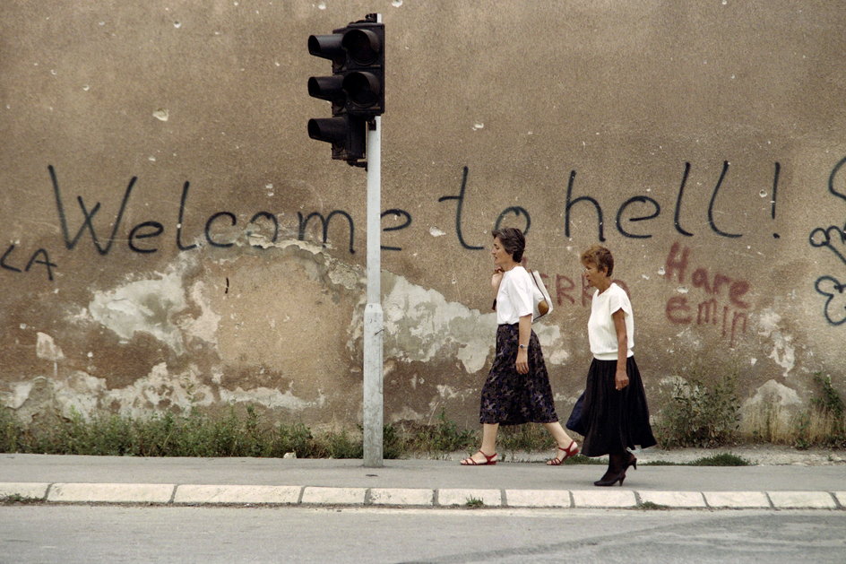 Kobiety przechadzające się Aleją Snajperów na tle napisu "Witamy w piekle" (1993 r.)