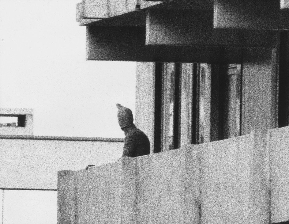 Zamaskowany terrorysta na balkonie budynku w wiosce olimpijskiej.