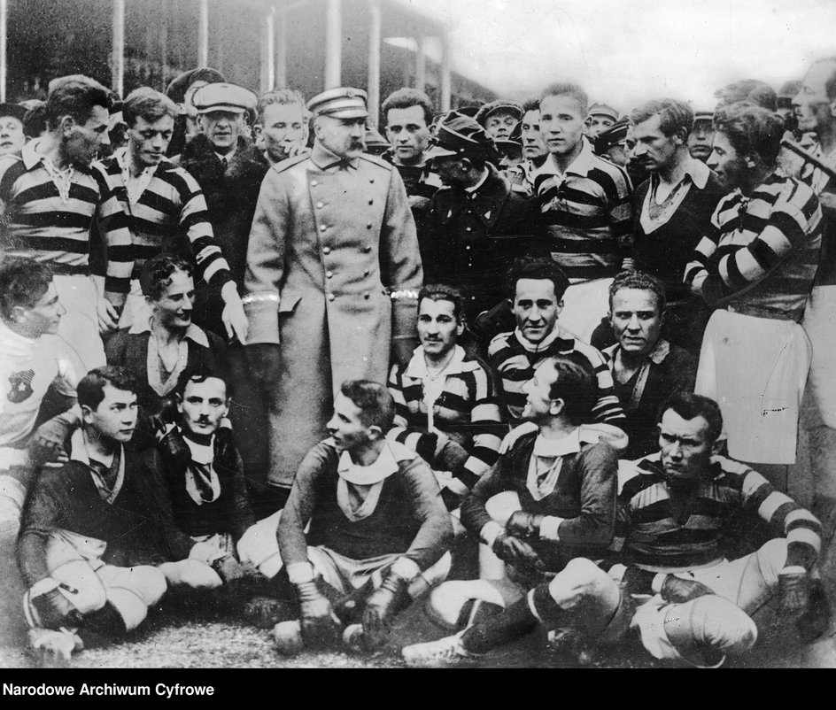 Marszałek Józef Piłsudski w otoczeniu zawodników Pogoni Lwów i Wisły Kraków na stadionie Wisły. Stoją od lewej: Henryk Reyman, Stefan Wójcik, prezes Aleksander Dembiński (w czapce), Władysław Krupa (na prawo za marszałkiem), Edward Garbien (w mundurze), Mieczysław Balcer (na prawo od E. Garbiena). Siedzą: Karol Henke, Bronisław Fichtel, Edward Gulisz, Franciszek Giebartowski, Marian Markiewicz.