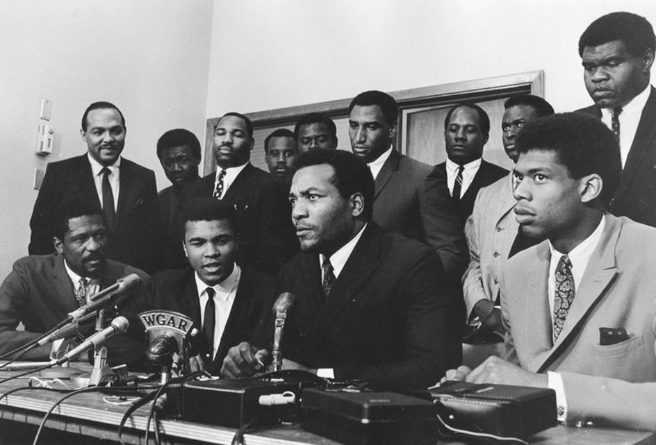 Od lewej do prawej: Bill Russell, Muhammad Ali, Jim Brown i Kareem Abdul Jabbar. Stoją za nimi: Carl Stokes, Walter Beach, Bobby Mitchell, Sid Williams, Curtis McClinton, Willie Davis, Jim Shorter i John Wooten. Czołowi Afroamerykańscy sportowcy udzielający wsparcia Alemu. 4 czerwca 1967 r.