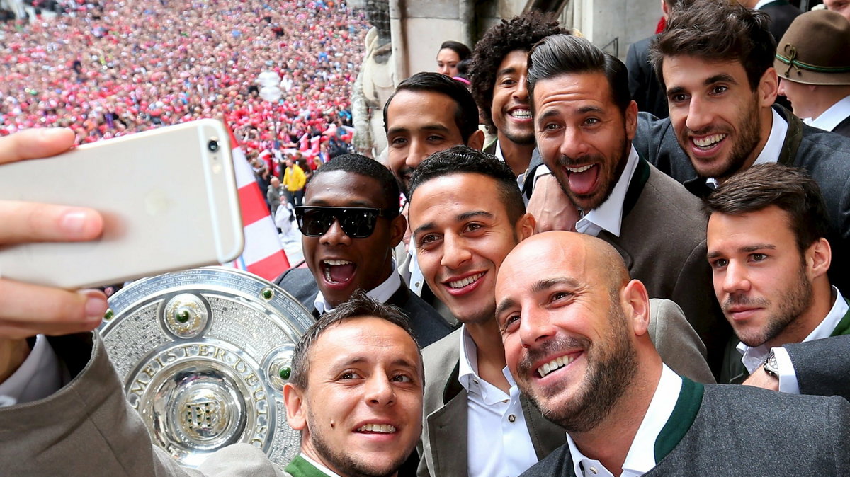 Rafinha of Bayern Munich takes a picture with team mates celebrate winning the German Championship title on the town hall balcony at Marienplatz in Munich