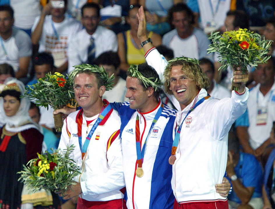 Mateusz Kusznierewicz na podium Igrzysk Olimpijskich a Atenach. Obok niego stoją Ben Ainslie i Rafael Trujillo. (fot. AFP)