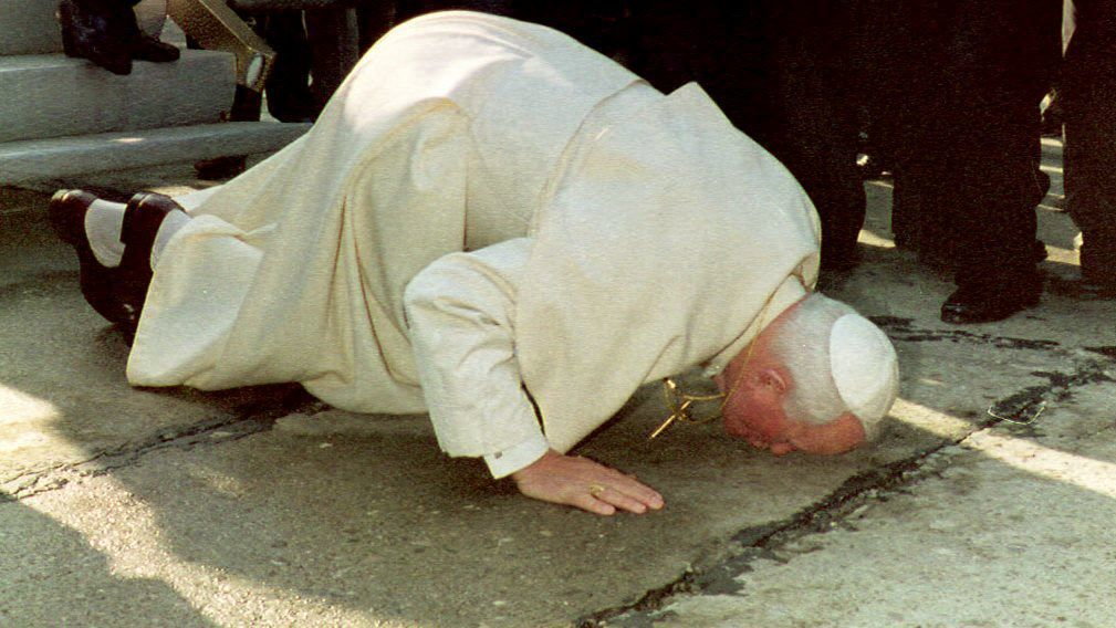 Papież Jan Paweł II całuje ziemię po przylocie na lotnisko w Tiranie (1993 r.)