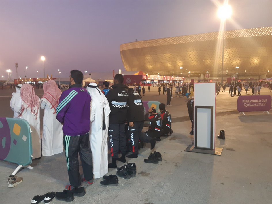 Minuty przed finałem, muzułmańscy policjanci i obsługa mundialu modlą się pod Lusail Iconic Stadium.