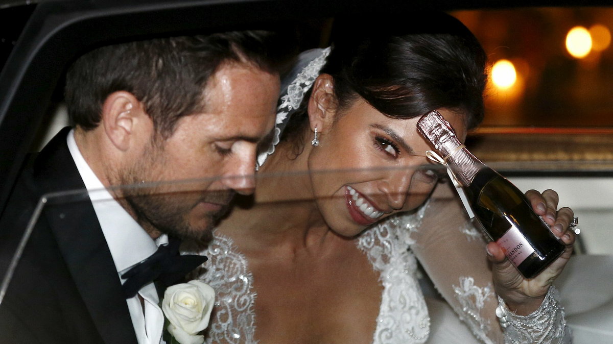 British TV personality Christine Bleakley smiles as she holds a miniature bottle of champagne while she and her husband, former Chelsea and England soccer player Frank Lampard, leave church after their wedding in London