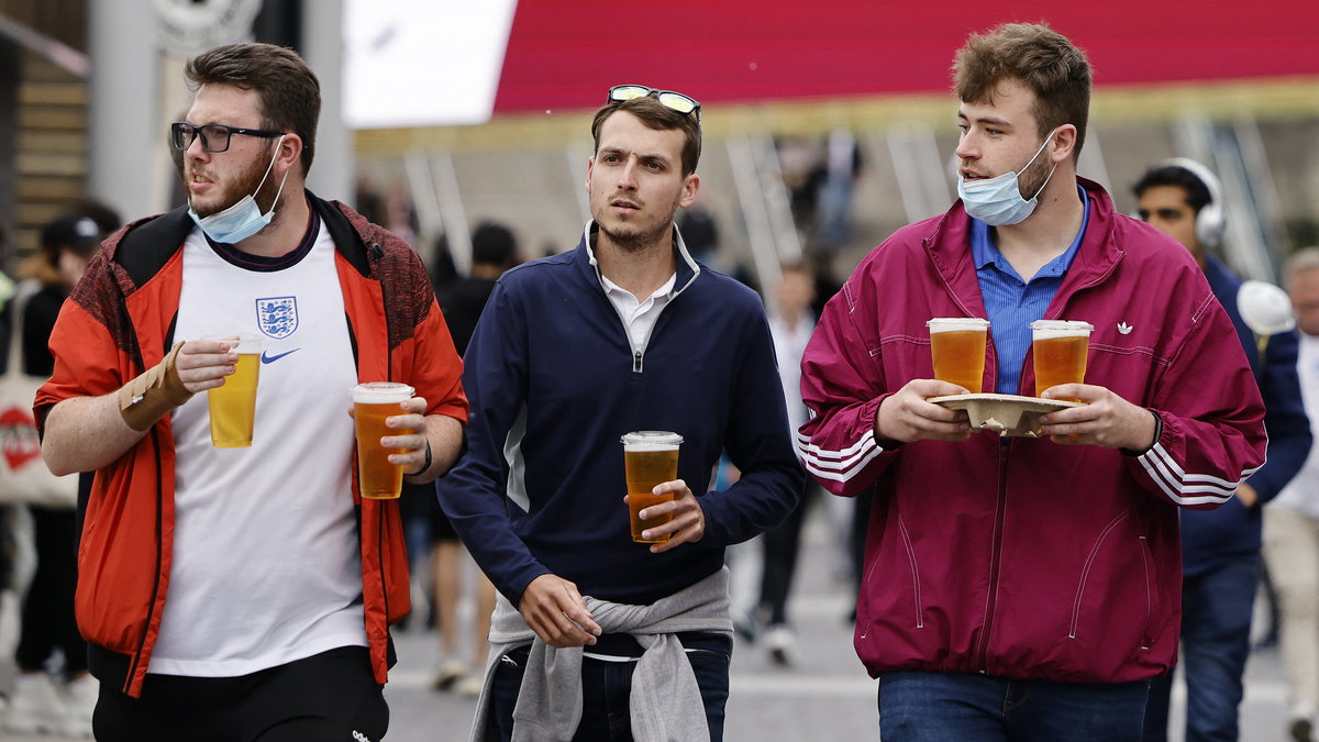 Angielscy kibice spacerujący z piwem obok stadionu Wembley