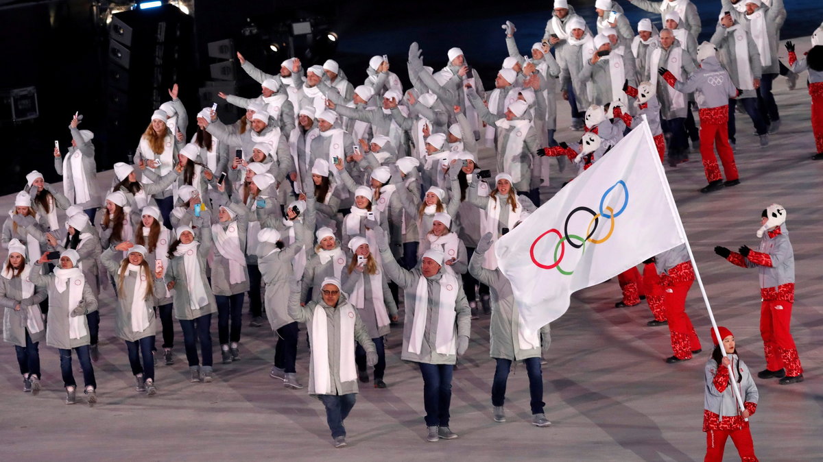 Wolontariusz niesie flagę Olimpijczyków z Rosji