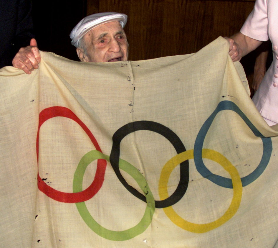 Hal Prieste trzymający oryginalną olimpijską flagę z igrzysk w 1920 roku