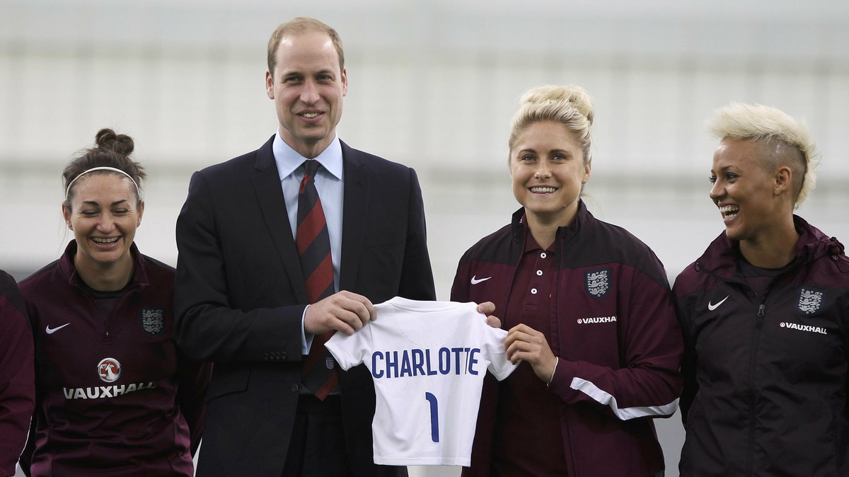 Britain's Prince William holds a shirt with his new daughter's name during a visit to the England ladies soccer World Cup squad at St George's Park, Burton