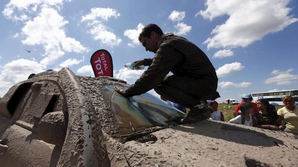 Torlaschi, co-pilot of Pons of Spain, cleans their Ford car with water at the end of the second stage in the Dakar Rally 2016 in Cordoba province