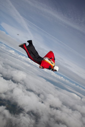 Skydiver in special wingsuit is flying over clouds